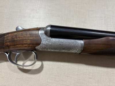 Espingarda dupla com detalhes em madeira e metal gravado.