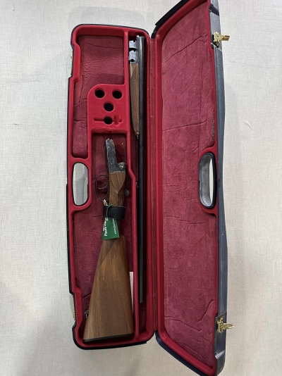 Estojo de espingarda aberto com interior em veludo vermelho e espingarda desmontada