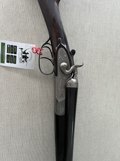 Espingarda de caça em madeira escura com cano preto e etiqueta Sporting