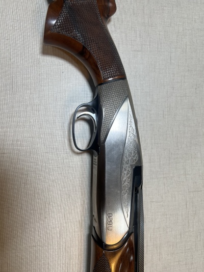 Espingarda de madeira e metal com detalhes gravados e número 18828 em fundo bege