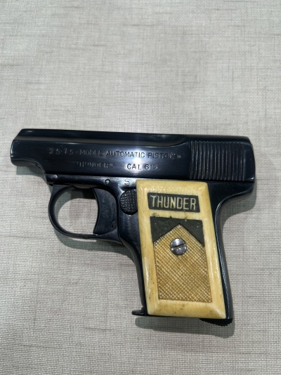 Revólver pequeno metal escuro com empunhadura clara e texto 'THUNDER'