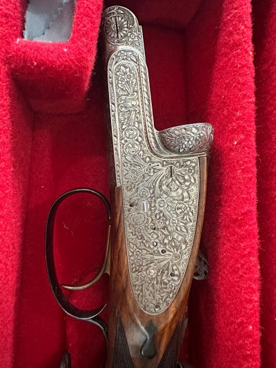 Arma de fogo decorada com gravações florais numa caixa vermelha de veludo