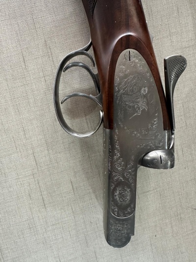 Espingarda de canos duplos com gravuras florais e de cães e madeira castanha polida sobre tecido cinza
