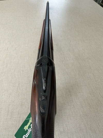 Espingarda de canos duplos com coronha de madeira escura sobre tecido bege