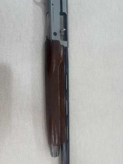 Espingarda com cano preto e coronha em madeira polida sobre tecido claro