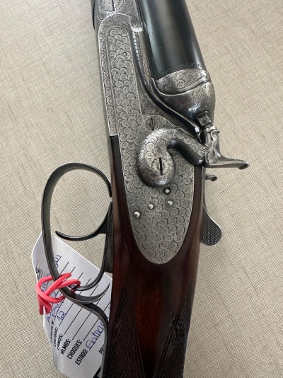 Espingarda dupla com madeira escura e metal gravado detalhadamente
