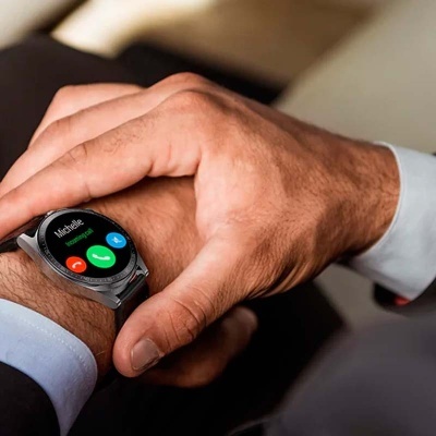 Relógio inteligente prateado com ecrã digital colorido a mostrar chamada de 'Michele' no pulso de homem de camisa branca