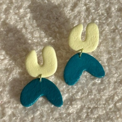 Brincos abstratos amarelos e azuis sobre fundo de tecido branco