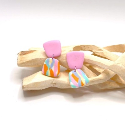 Brincos coloridos sobre galhos de madeira clara