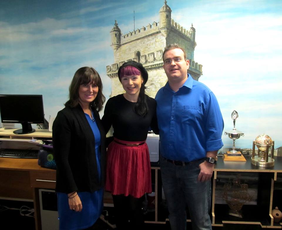 Três pessoas posam em sala de escritório com mural da Torre de Belém ao fundo