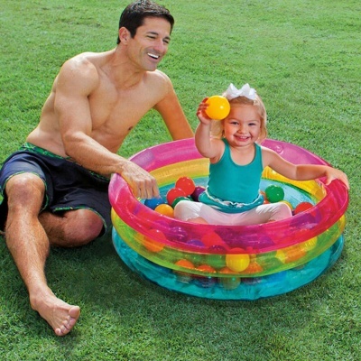 Piscina insuflável infantil colorida com bolas e crianças brincando na relva