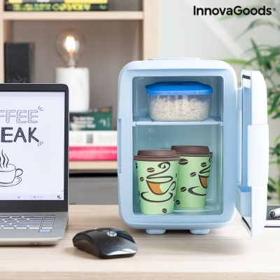 Mini frigorífico portátil branco e azul claro com copos de café e recipiente de plástico no interior numa mesa com computador portátil.
