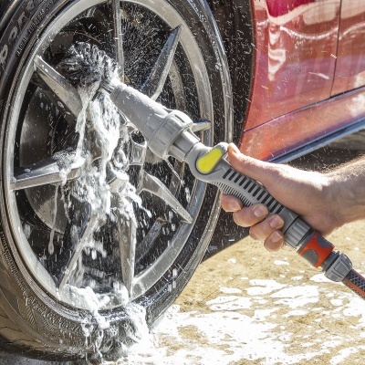Lavagem de roda de carro com mangueira borrifando água e espuma