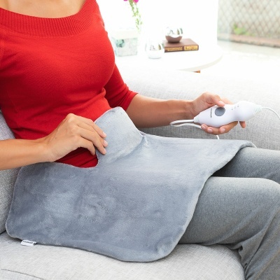 Pessoa usando almofada térmica elétrica cinza no sofá