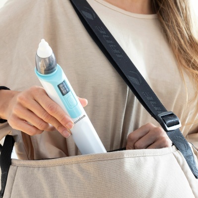 Dispositivo branco e azul com visor e botão, a ser colocado em mala bege.