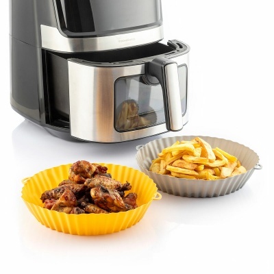 Air fryer com cesto inox e duas tigelas em silicone com asas de frango e batatas fritas