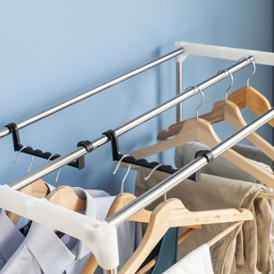 Suporte para cabides em metal e plástico com cabides de madeira e roupas penduradas