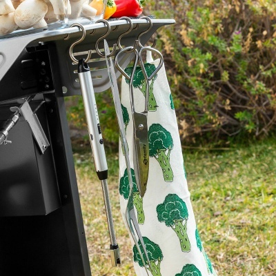 Grelhador com ganchos e utensílios pendurados ao ar livre