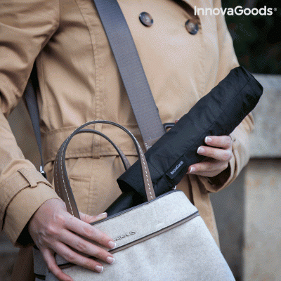 Pessoa com casaco bege a colocar guarda-chuva compacto preto na mala bege