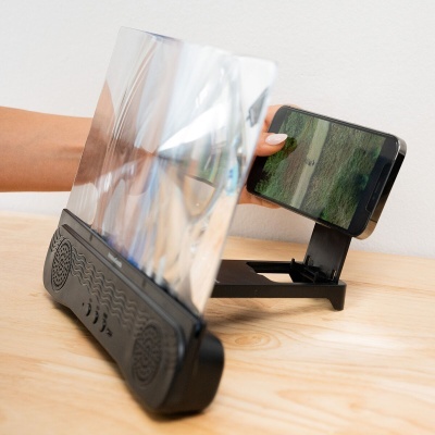Suporte preto com amplificador transparente e colunas para smartphone numa mesa de madeira