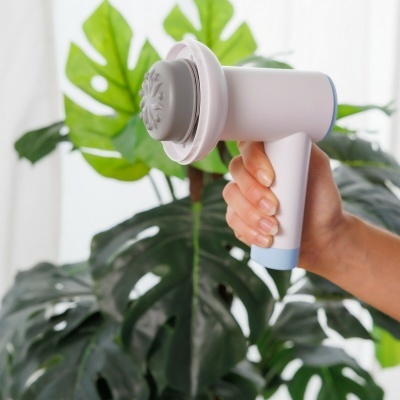 Dispositivo portátil branco e cinzento para massagem segurado por uma mão