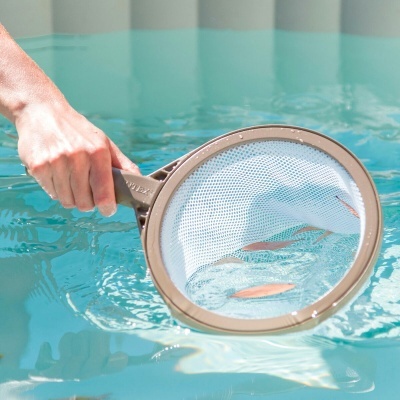 Rede de limpeza para piscina com aro bege e malha branca na água