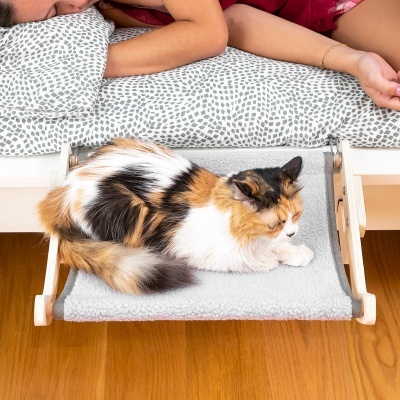 Cama suspensa para gato montada sob uma cama com roupa branca e padrão cinzento