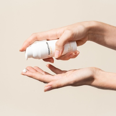 Mãos a aplicar creme branco de dispenser branco com texto Innovacosm