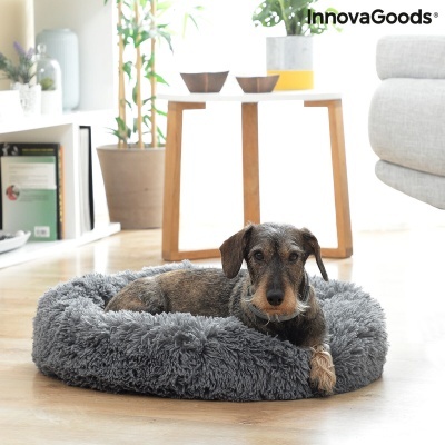 Cama para cão cinza peluda redonda numa sala moderna com planta e mesa branca