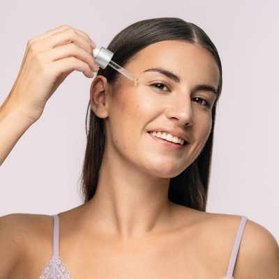 Mulher a aplicar soro facial com conta-gotas no rosto