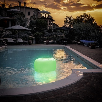 Piscina exterior com puff insuflável verde iluminado à noite