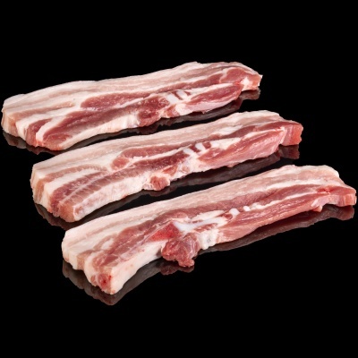 Três fatias de entremeada de porco crua sobre superfície preta