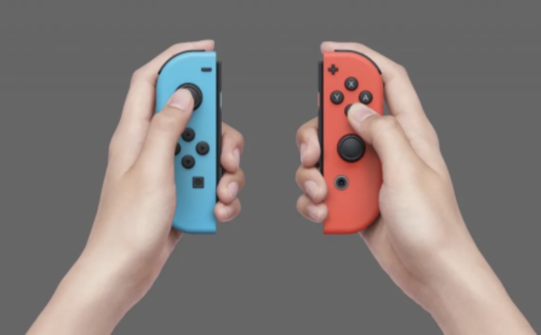 Pack 2 Comandos Joy-Con NINTENDO 2 Mãos segurando controladores Nintendo Switch Joy-Con azul e vermelho