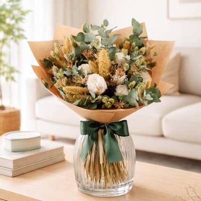 Bouquet de flores secas em vaso de vidro sobre mesa de madeira