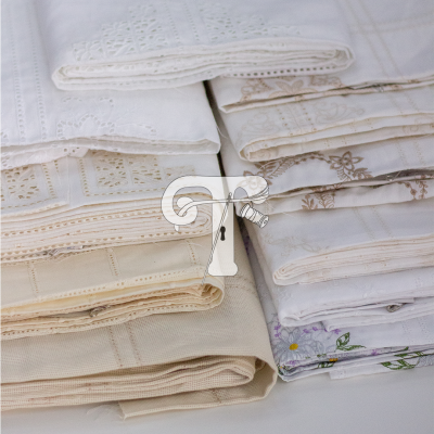 Tecidos dobrados com bordados em branco, bege e cinzento claro