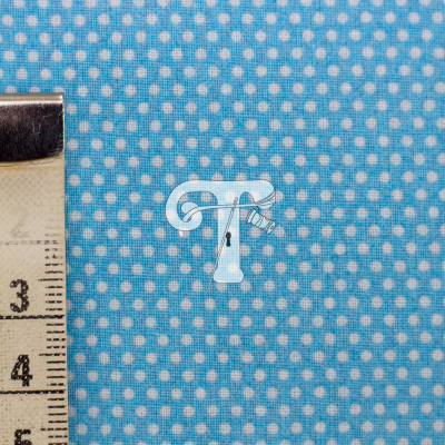Tecido azul com bolinhas brancas ao lado de fita métrica.