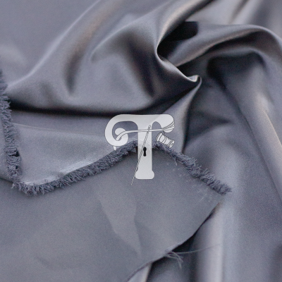 Tecido cinzento suave com bordas desfiadas e símbolo branco em forma de T