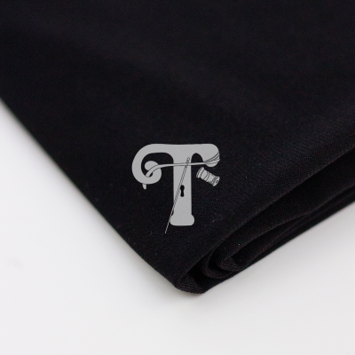 Tecido preto com símbolo branco de letra T com agulha e linha