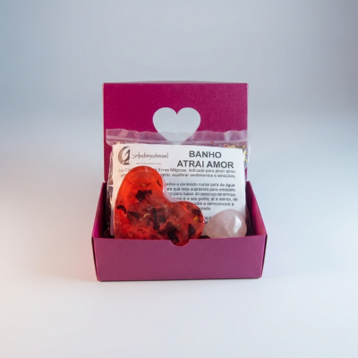 Caixa cor de vinho com coração branco, pacote de ervas com texto e duas pedras dentro