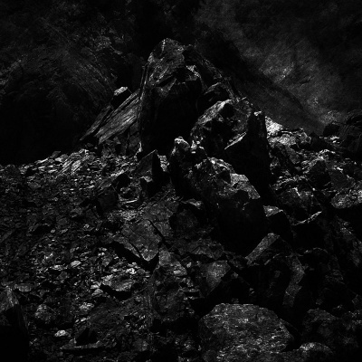 Monte de carvão preto com textura rugosa em ambiente rochoso escuro