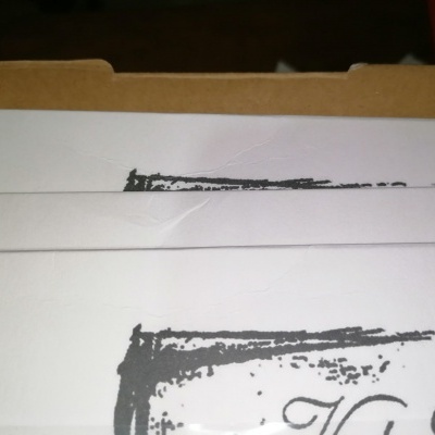 Encadernação branca com texto parcial em tinta preta cursiva sobre fundo escuro