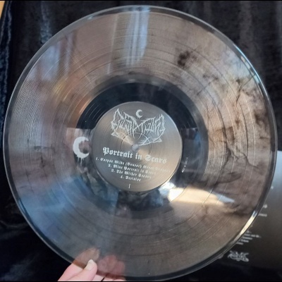 Disco vinil transparente com manchas e etiqueta central preta com texto branco