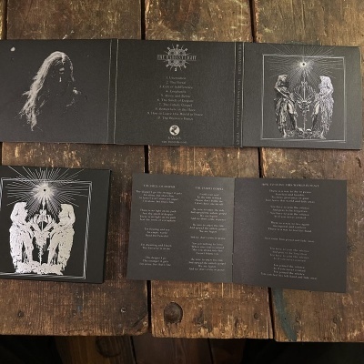 Digipack de CD com ilustração em preto e branco e texto em inglês sobre uma mesa de madeira