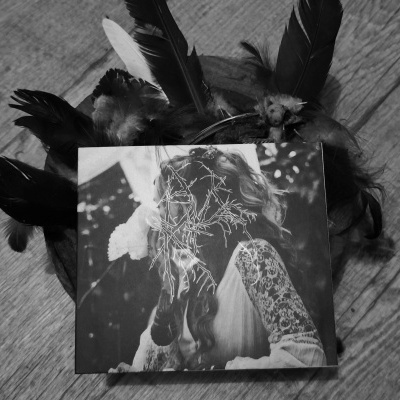 Objeto com penas e fotografia em preto e branco sobre superfície de madeira