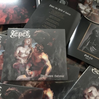 CDs e folhetos do álbum 'Ingenium Satanæ' da banda Kepet com capa artística e texto branco