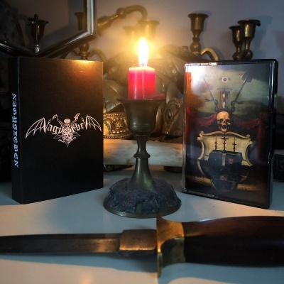 Vela acesa em castiçal metálico com livro e caixa de CD ao lado sobre mesa branca