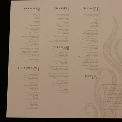 Menu impresso em papel branco com texto em colunas e padrão decorativo cinza claro