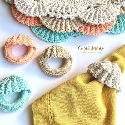 Anéis de guardanapos em crochet multicolor sobre toalha amarela com texto Coral Sands