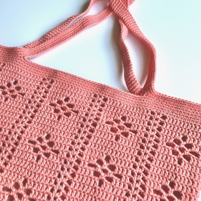 Sacola de crochê cor-de-rosa com padrão floral e alças largas