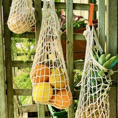 sacos de rede de algodão com frutas pendurados numa estrutura de madeira num jardim